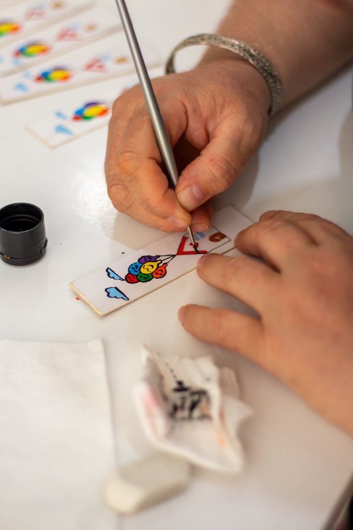 gallery-01 Close-up of hands painting vibrant designs on wooden pieces, showcasing creativity.