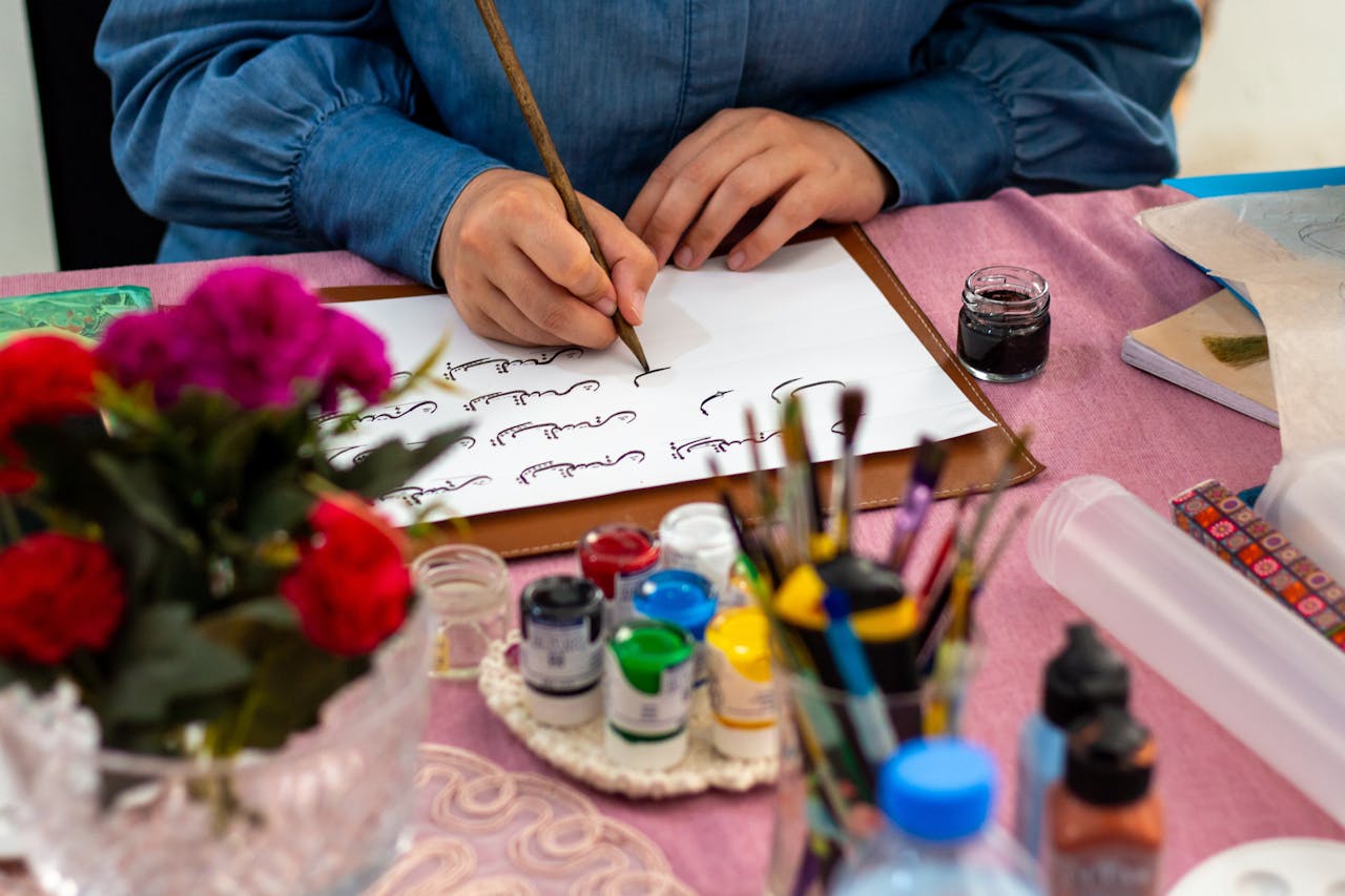 gallery-06 Close-up of calligraphy on paper with vibrant ink and brushes nearby.