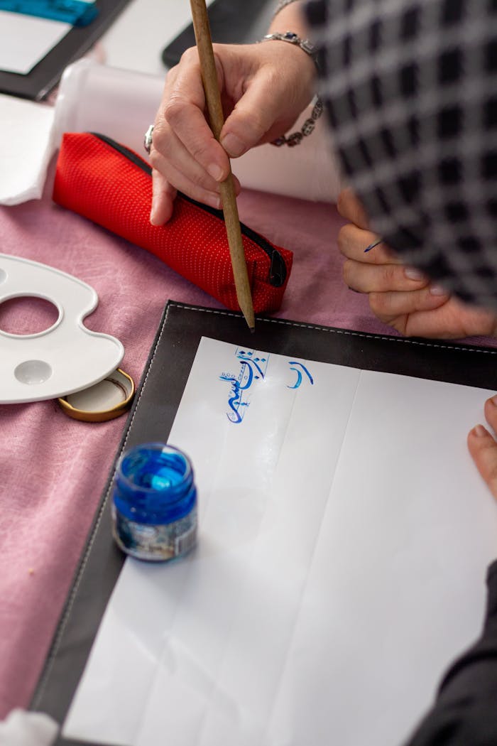 portfolio-02 Hands practicing calligraphy with ink on paper, showcasing artistic creation.